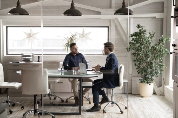 A rep and an employee meet around a conference room table.